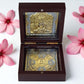 Jain Tirthankar Yantra in polished wooden box, plated in gold and silver, surrounded by pink flowers.