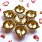 7-inch decorative mini urli bowl with 6 diya holders in brass finish, surrounded by rose petals.