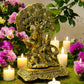 Brass Radha Krishna idol under tree with antique finish, surrounded by flowers and candles for spiritual home decor.